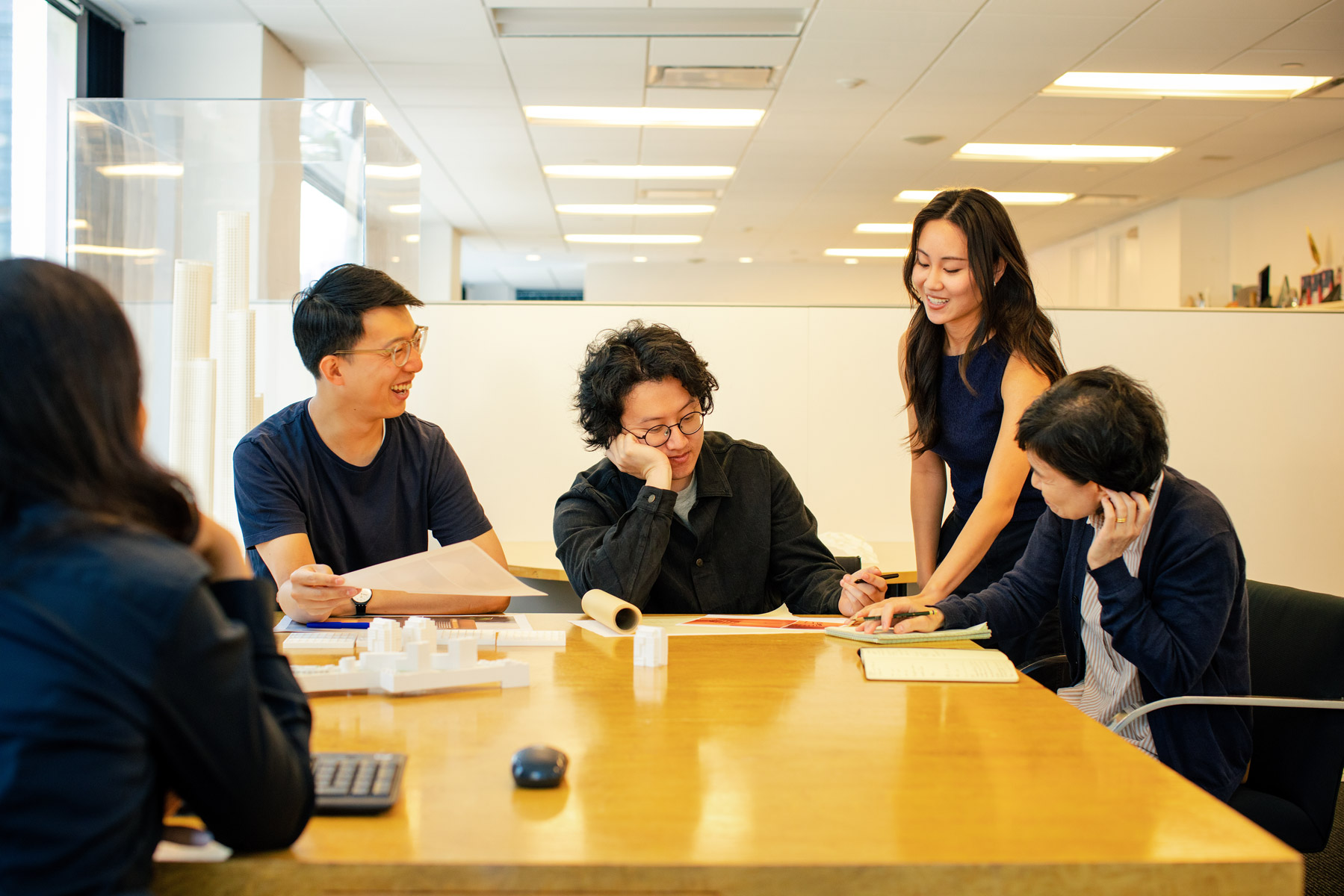 Design team meeting in a conference room, discussing project drawings and models.